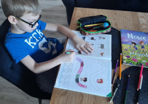 Chłopiec wykonuje zadania w książce